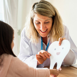 Smiling dentist showing patient smiling tooth