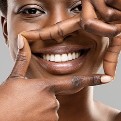 Woman framing her smile with four fingers