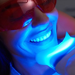 Woman smiling as uv light speeds up her teeth whitening application