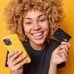 Woman holding yellow phone and credit card smiling