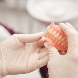 Gloved hands holding full dentures in Lisle, IL