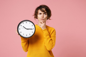 Woman holding a clock and wondering how long her Invisalign treatment will take