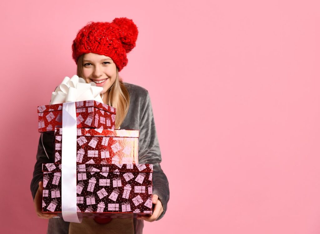 A teenage girl holding a stack of holiday gifts