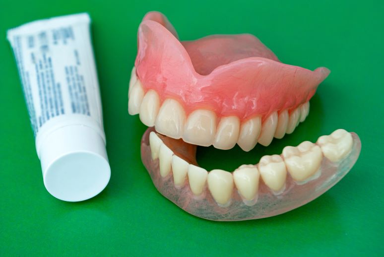 A pair of dentures with a tube of adhesive